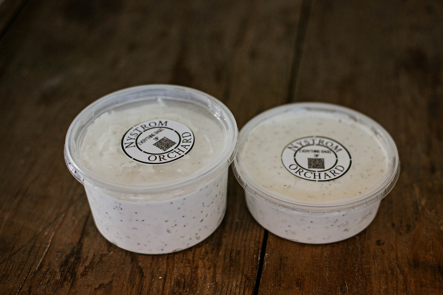 Two different sized containers of everything bagel dip on a wooden surface. Made in the kitchen of Nystrom Orchard in Worthington Minnesota.