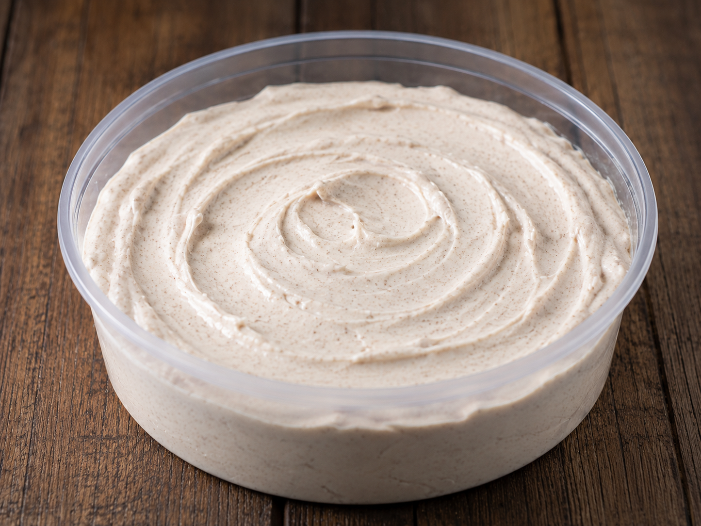 A clear 8 oz deli container with brown sugar cream cheese dip on a wooden surface. Made in the kitchen of Nystrom Orchard in Worthington Minnesota.