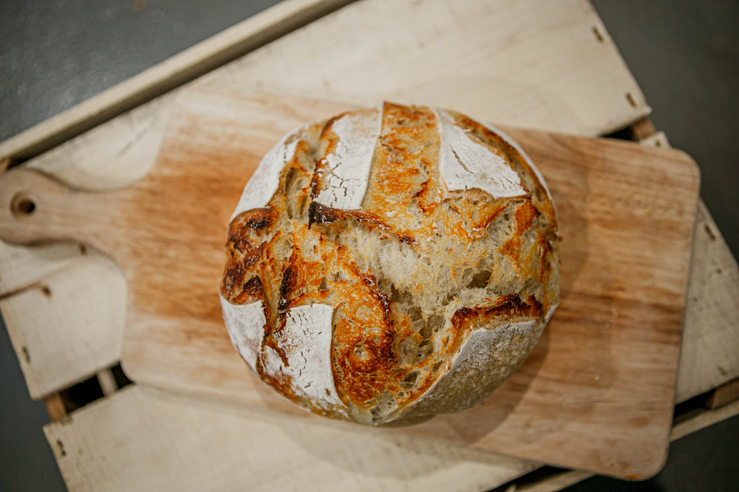 Loaf of rustic sourdough bread on a wooded cutting board. Baked in the kitchen of Nystrom Orchard in Worthington Minnesota.
