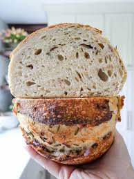 Hand holding a rustic loaf of sourdough bread cut in half to show the crumb on the inside. Baked in the kitchen at Nystrom Orchard in Worthington Minnesota.
