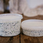 Two containers of creamy spinach dip with lids on a wooden surface with a blurred background. Made in the kitchen of Nystrom Orchard in Worthington Minnesota.