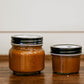 Two jars of salted caramel on a wooden surface. Made in the kitchen of Nystrom Orchard in Worthington Minnesota.
