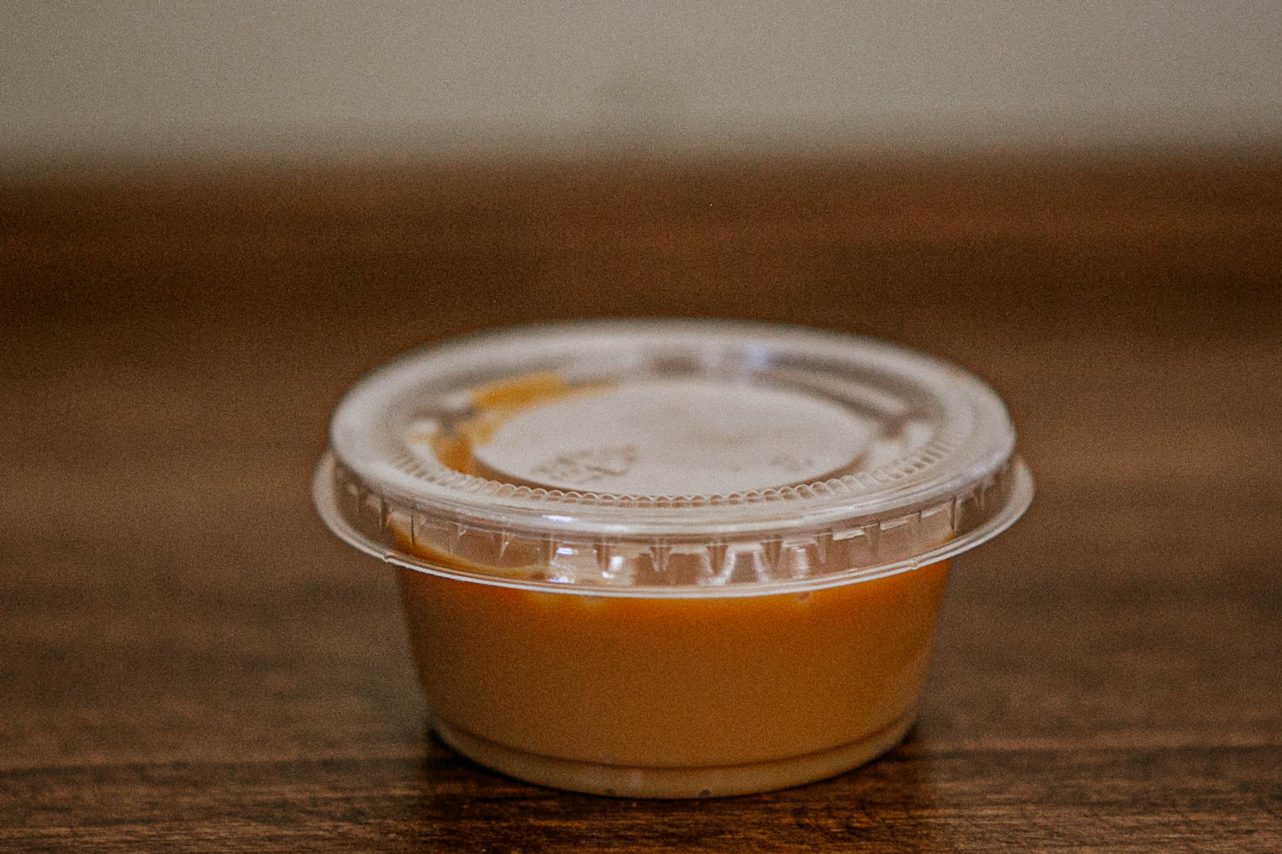2 oz. container of salted caramel with a lid on a wooden surface. Made in the kitchen of Nystrom Orchard in Worthington Minnesota.