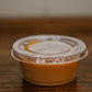 2 oz salted caramel in a plastic container with a lid on a wooden surface. Made in the kitchen of Nystrom Orchard in Worthington Minnesota.