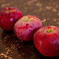 A row of Cortland apples on a wooden surface. Picked in Nystrom Orchard in Worthington Minnesota.