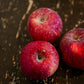 3 Haralson apples on a wooden surface. Picked in Nystrom Orchard in Worthington Minnesota.