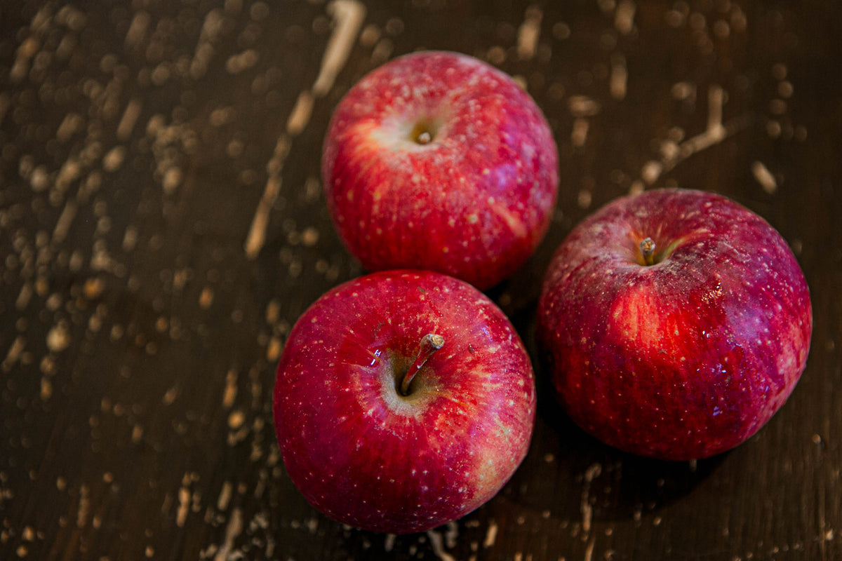 3 Haralson apples on a wooden surface. Picked in Nystrom Orchard in Worthington Minnesota.