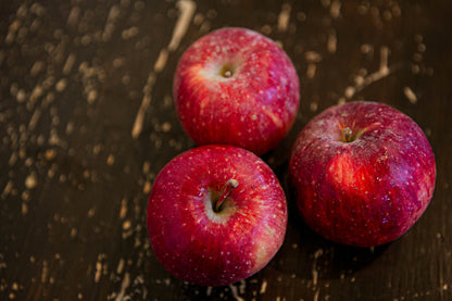 3 Haralson apples on a wooden surface. Picked in Nystrom Orchard in Worthington Minnesota.