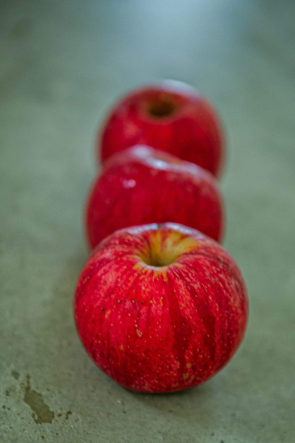 Three gala apples on a concrete surface. Picked at Nystrom Orchard in Worthington Minnesota.