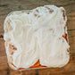 Four sourdough cinnamon rolls in a foil pan with cream cheese frosting on a wooden surface. Baked in the kitchen of Nystrom Orchard in Worthington Minnesota. 