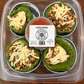 Plastic deli container with stuffed peppers and sauce labeled on a wooden surface. Made in the kitchen of Nystrom Orchard in Worthington Minnesota.