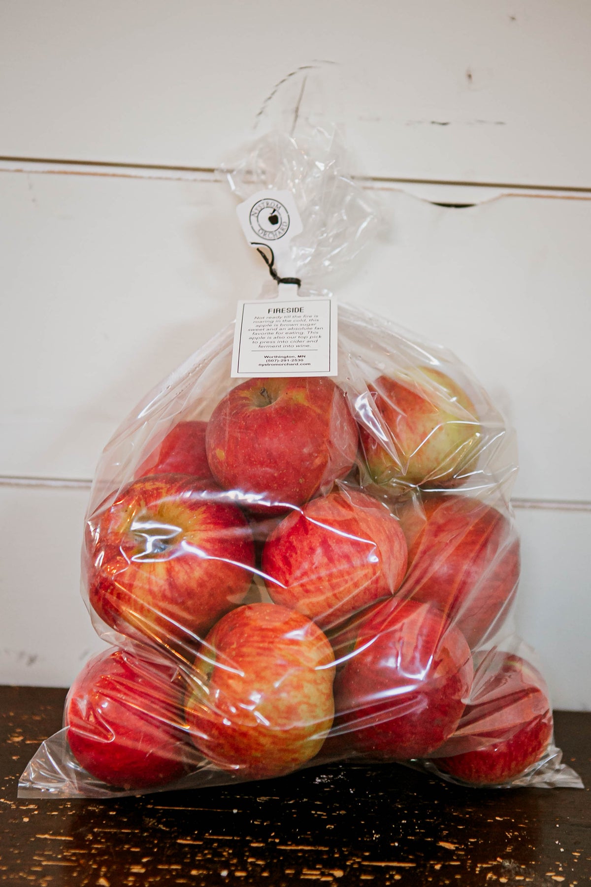 5 lb plastic bag of fireside apples on a wooden table with a white background. Picked in Nystrom Orchard in Worthington Minnesota.