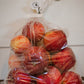 A clear 5lb plastic bag of Harlson apples on a wooden surface and a white background. Picked in Nystrom Orchard in Worthington Minnesota.