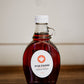 8 oz jug of maple syrup on a wooden surface with a white background. Sold by Nystrom Orchard in Worthington Minnesota.