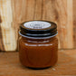 Jar of apple butter on a wooden cutting board. Crafted in the kitchen of Nystrom Orchard in Worthington Minnesota.