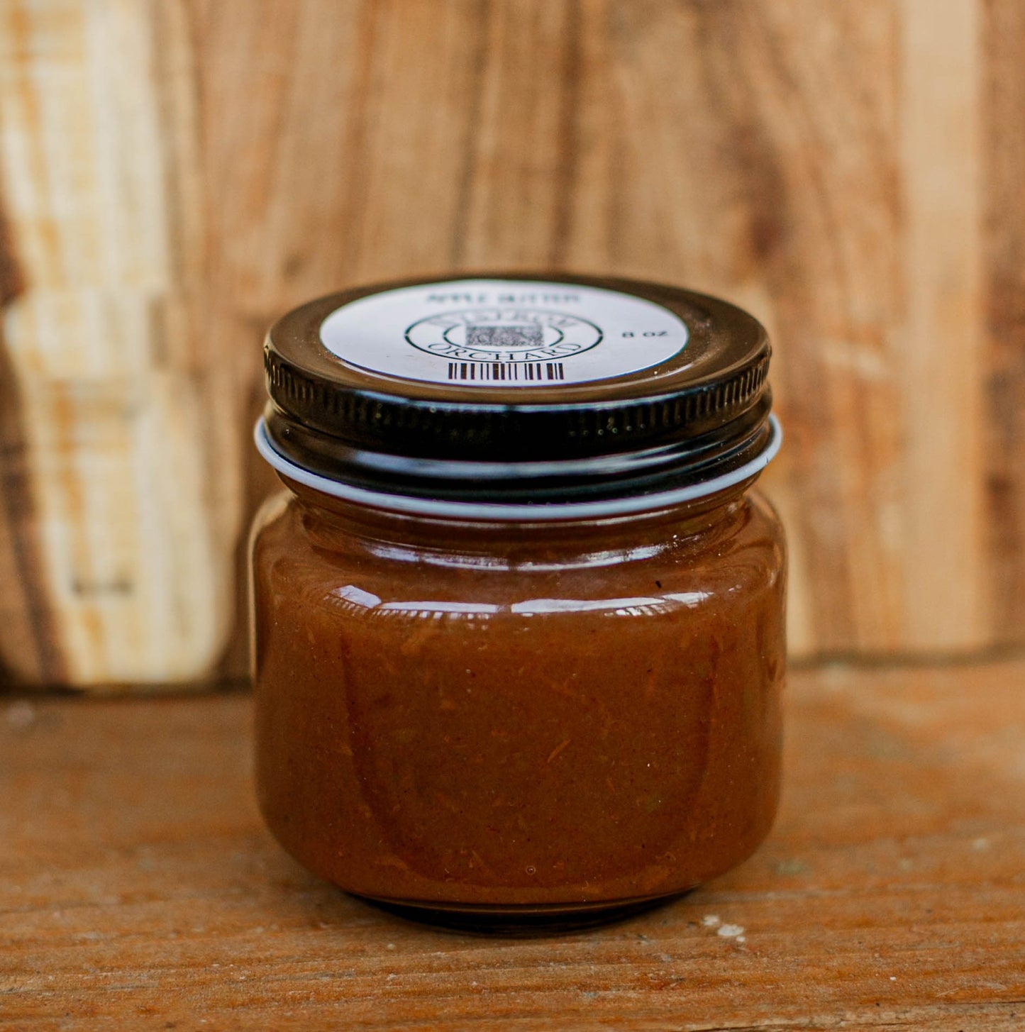 Jar of apple butter on a wooden cutting board. Crafted in the kitchen of Nystrom Orchard in Worthington Minnesota.
