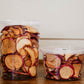 This image displays containers of apple chips, which appear to be a delicious and healthy snack option. The apple chips are neatly packaged in clear plastic tubs, allowing the viewer to see the crisp, evenly sliced apple pieces inside. Dried in the kitchen of Nystrom Orchard in Worthington Minnesota.