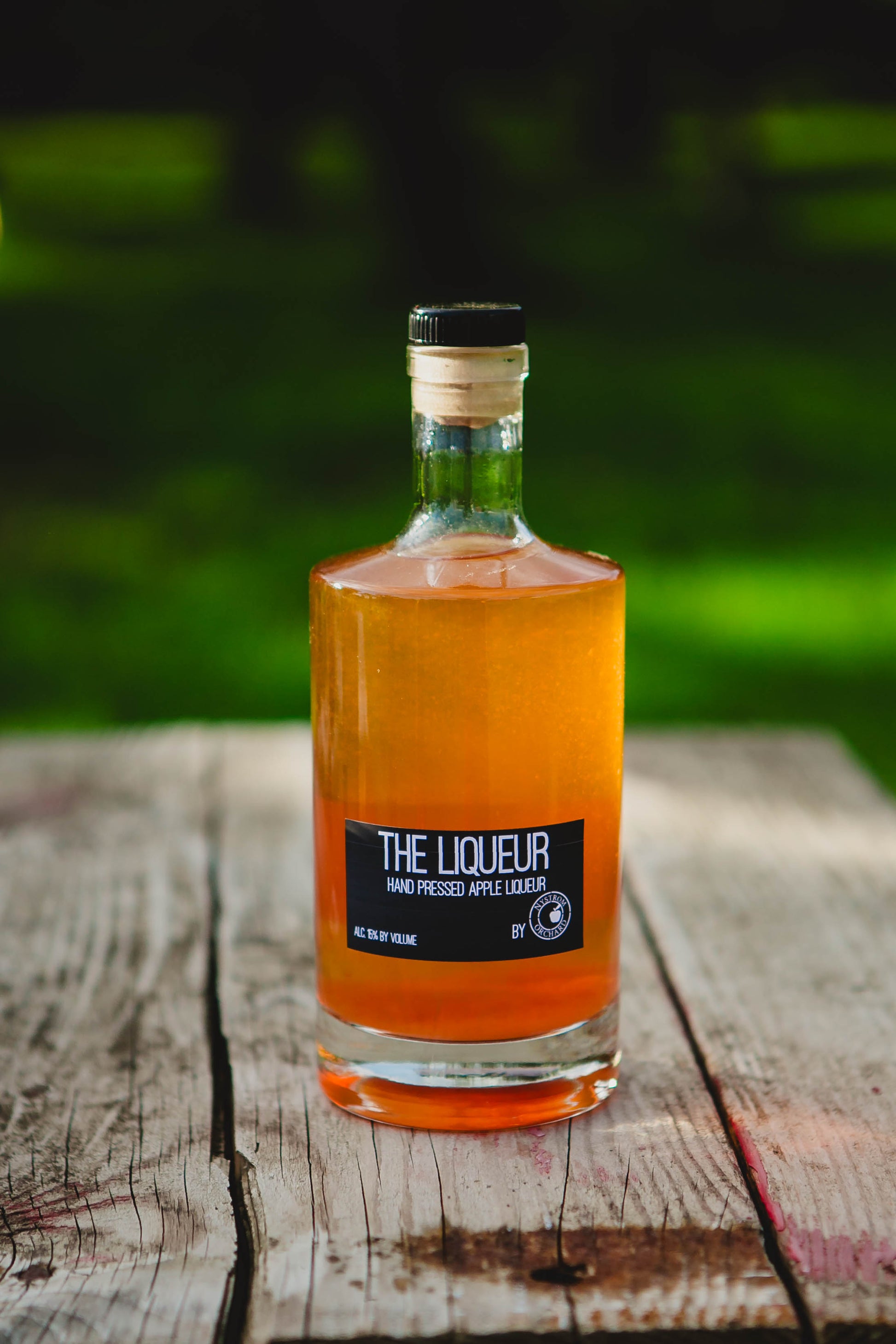 Apple Liqueur on a wooden table in the orchard. Made in the kitchen of Nystrom Orchard in Worthington Minnesota.