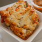 A photo of a single biscuit with cheddar cheese apples and herbs, placed on a white plate. Baked in the kitchen of Nystrom Orchard in Worthington Minnesota.