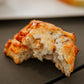 Apple cheddar rosemary biscuit broken in half on a dark surface with a blurry background. Baked in the kitchen of Nystrom Orchard in Worthington Minnesota.