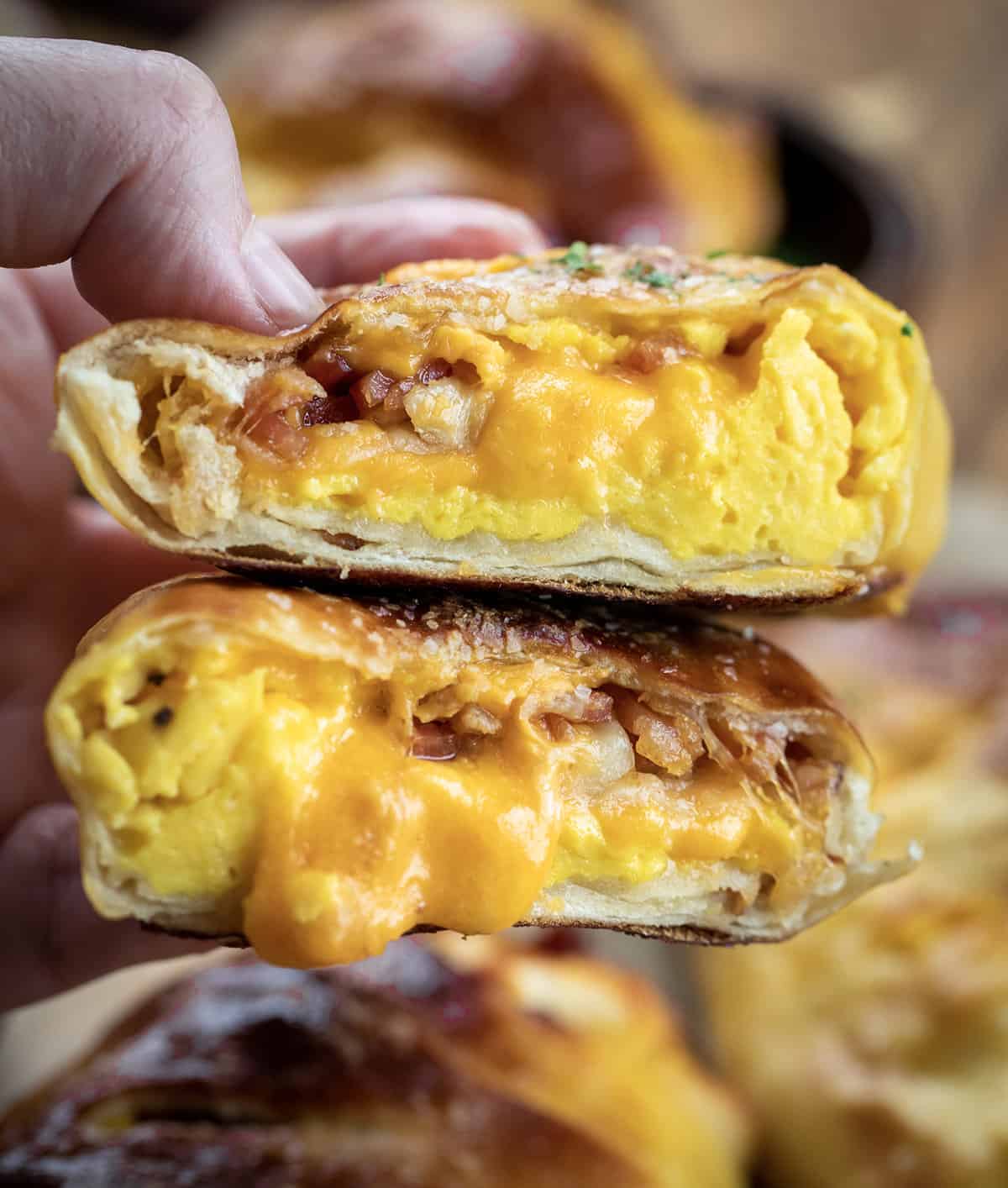 Soft pretzel wrap cut in half to show that its full of eggs, cheese and bacon with a blurry background. Made in the kitchen of Nystrom Orchard in Worthington Minnesota.