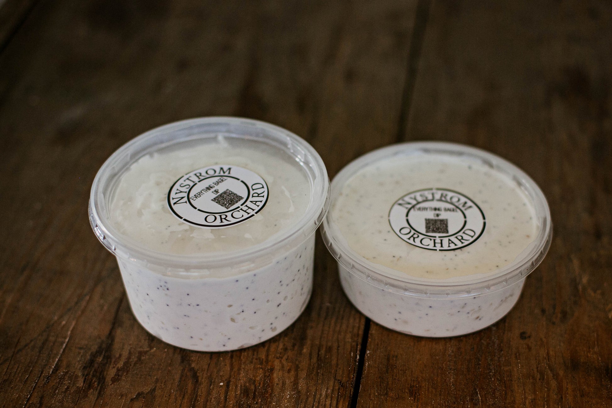 Two different sized containers of everything bagel dip on a wooden surface.  Made in the kitchen of Nystrom Orchard in Worthington Minnesota.