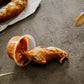 Broken piece of soft pretzel dipped in caramel on a dark surface with sauce smeared beside. Baked in the kitchen of Nystrom Orchard in Worthington Minnesota.