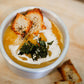 Bowl of butternut squash bisque with sourdough croutons and crispy sage on a wooden background. Made in the kitchen of Nystrom Orchard in Worthington Minnesota.