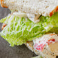 Close-up of a sandwich sourdough bread with lettuce and chicken salad on a dark surface. Prepared in the kitchen at Nystrom Orchard in Worthington Minnesota.