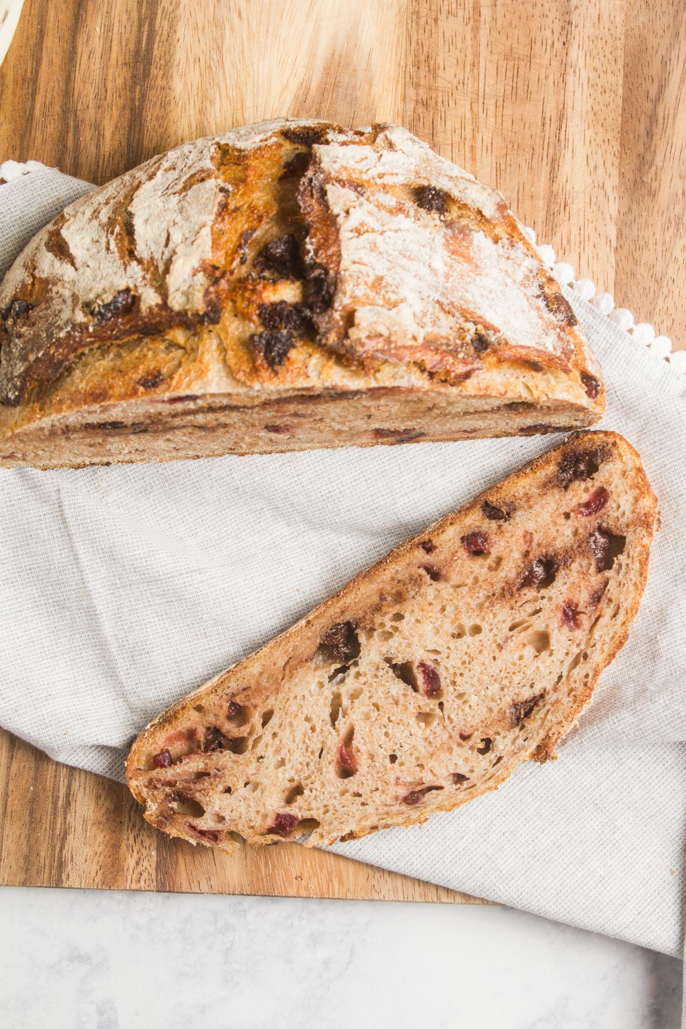 Rustic loaf of sourdough bread on a white cloth on a wooden cutting board. Baked in the kitchen of Nystrom Orchard in Worthington Minnesota.  
