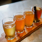 A flight of cold pressed cider on a wooden board on a metal table. Pressed in the kitchen at Nystrom Orchard in Worthington Minnesota.