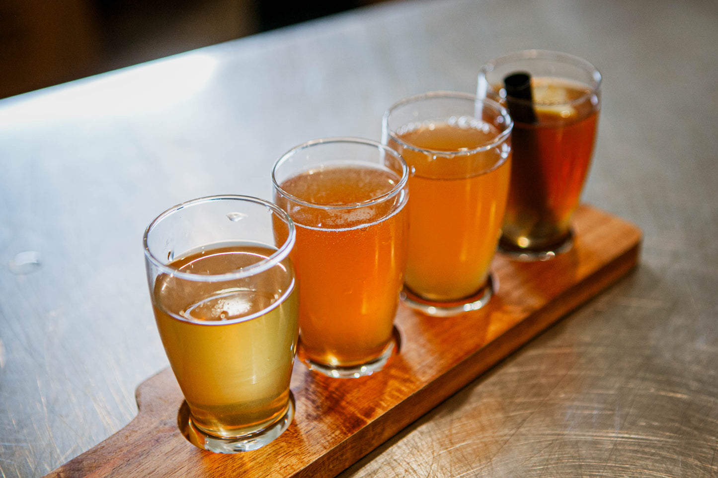 A flight of cold pressed cider on a wooden board on a metal table. Pressed in the kitchen at Nystrom Orchard in Worthington Minnesota.