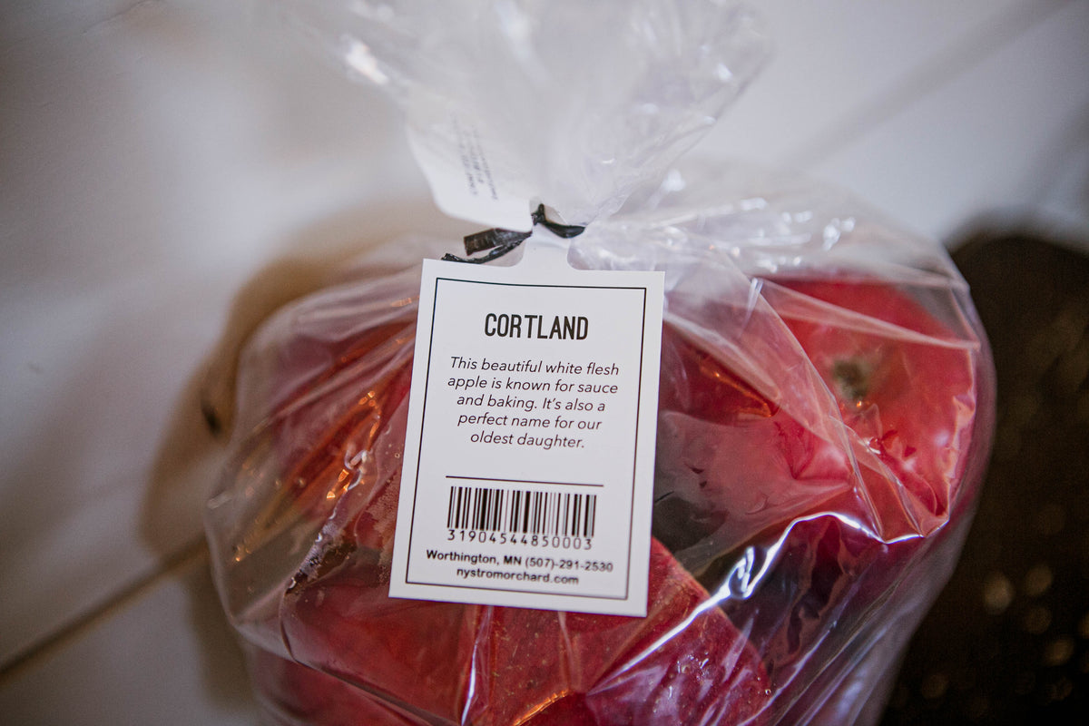 Cortland tag on a bag of Cortland apples with a blurry background. Picked in Nystrom Orchard in Worthington Minnesota.