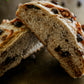 Rustic loaf of Dark Chocolate walnut sourdough on a dark surface cut in half and propped on each other. Baked in the kitchen at Nystrom Orchard in Worthington Minnesota.