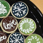 Decorative cookies with snowflakes, wreaths, and 'love' text on a black plate. Baked in the kitchen at Nystrom Orchard in Worthington Minnesota.