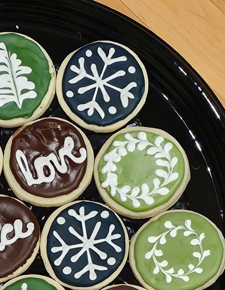 Decorative cookies with snowflakes, wreaths, and 'love' text on a black plate. Baked in the kitchen at Nystrom Orchard in Worthington Minnesota.