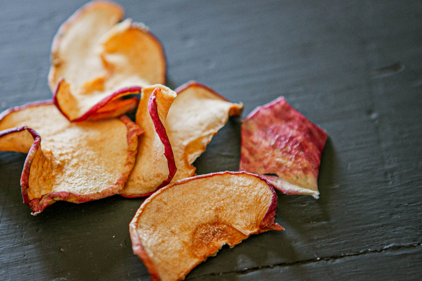 Dried apple chips on a wooden surface. Dried in the kitchen of Nystrom Orchard in Worthington Minnesota.