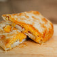 Egg cheese and bacon filled hot pocket on a wooden cutting board. Baked in the kitchen of Nystrom Orchard in Worthington Minnesota.