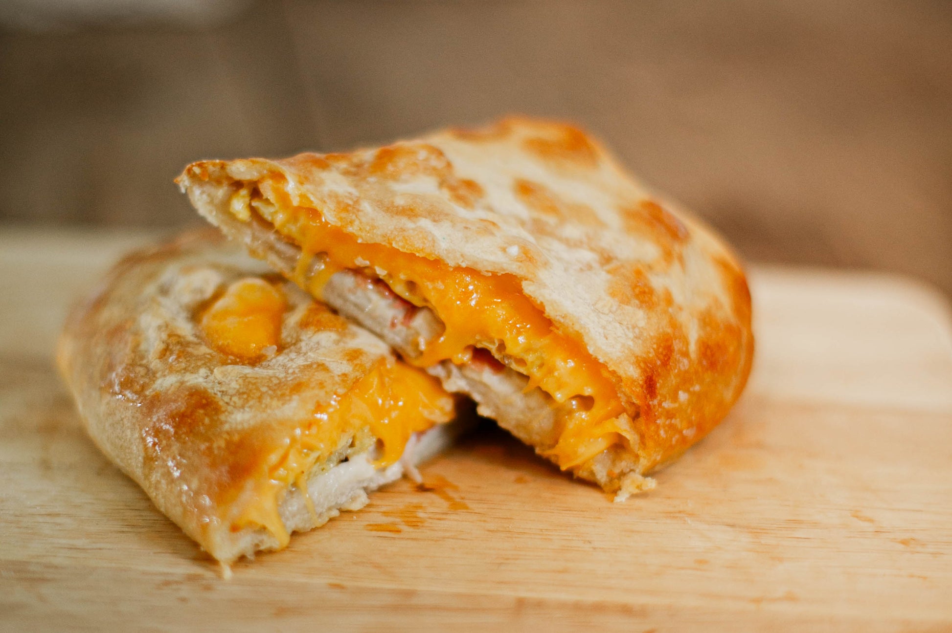 Egg cheese and bacon filled hot pocket on a wooden cutting board. Baked in the kitchen of Nystrom Orchard in Worthington Minnesota.