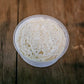 Plastic container filled with everything bagel dip on a wooden surface.  Made in the kitchen of Nystrom Orchard in Worthington Minnesota.