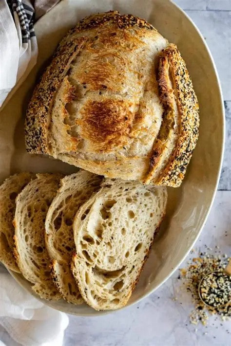 Sliced rustic everything bagel gouda sourdough bread on a white plate with a marble background. Made in the kitchen at Nystrom Orchard in Worthington Minnesota. 