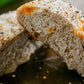 Loaf of sourdough cheddar everything bagel seasoning bread cut in half to show the fluffy interior on a dark surface. Baked in the kitchen at Nystrom Orchard in Worthington Minnesota.