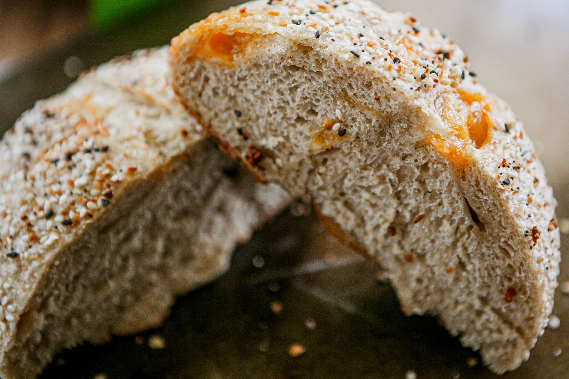 Loaf of sourdough cheddar everything bagel seasoning bread cut in half to show the fluffy interior on a dark surface. Baked in the kitchen at Nystrom Orchard in Worthington Minnesota.