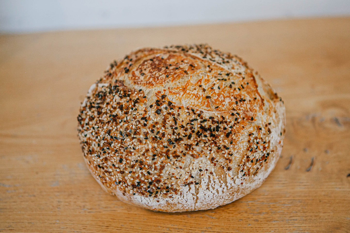 A freshly baked loaf of artisan everything bagel sourdough bread on a wooden cutting board. Baked in the kitchen of Nystrom Orchard in Worthington Minnesota.