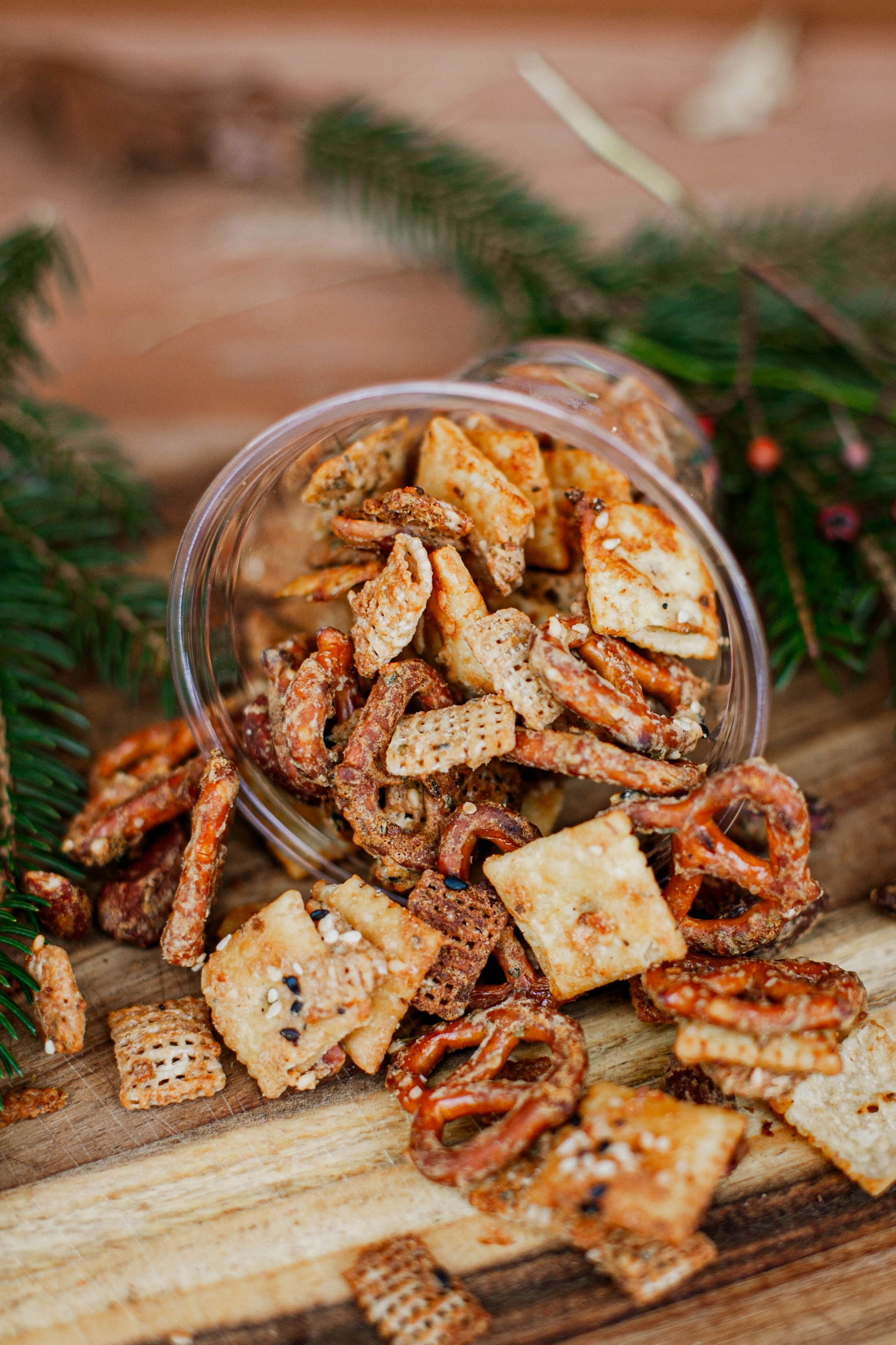 Sourdough snack mix in a clear container on a wooden surface with greenery in the background. Made in the kitchen of Nystrom Orchard in Worthington Minnesota.