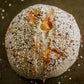 Artisan loaf of sourdough bread full of cheddar cheese and the top is coated with everything bagel seasoning on a dark surface. Baked in the kitchen at Nystrom Orchard in Worthington Minnesota. 