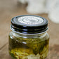 Glass jar of garlic dipping olive oil with parmesan cheese and fresh basil and a black lid on a wooden surface. Made in the kitchen at Nystrom Orchard in Worthington Minnesota. 
