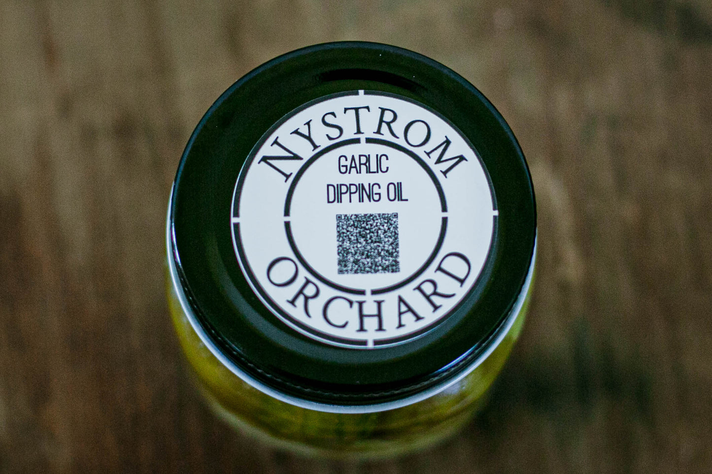 Jar of garlic dipping oil with 'Nystrom Orchard' label on a wooden surface