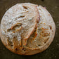 Rustic loaf of garlic and herb sourdough on a dark surface. Baked in the kitchen at Nystrom Orchard in Worthington Minnesota.