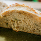 Loaf of garlic and herb sourdough cut in half so you can see the crumb on a dark surface. Baked in the kitchen at Nystrom Orchard in Worthington Minnesota.